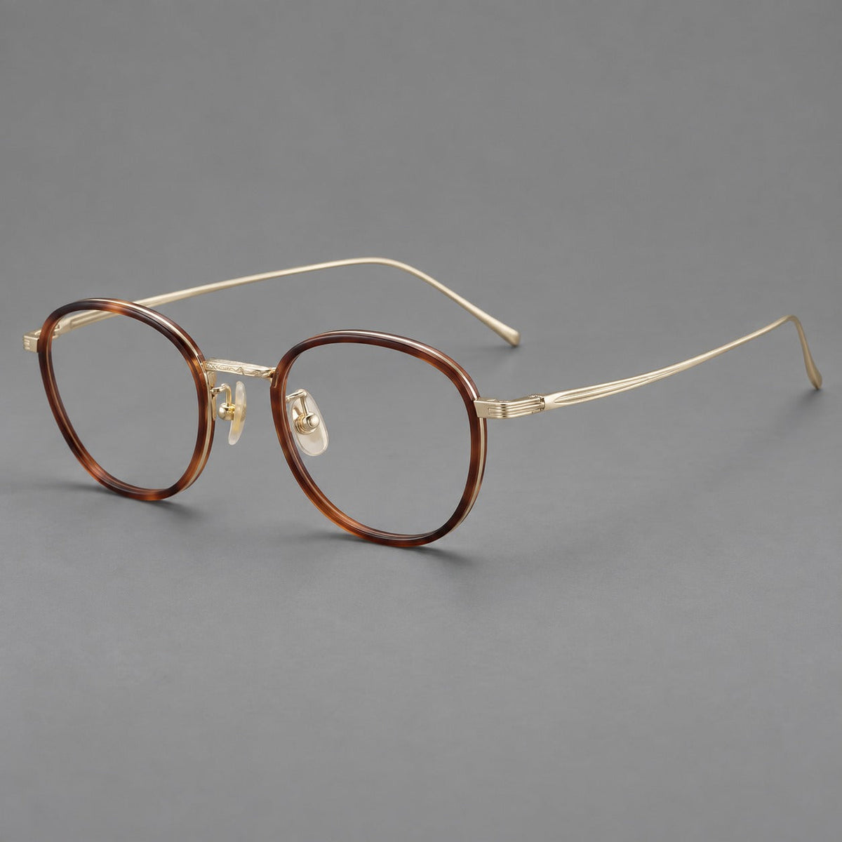 Montatura rotonda vintage in acetato e titanio con ponte inciso e aste sottili — immagine del prodotto